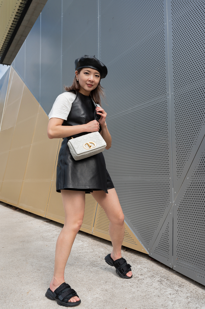 A guest wears a gray fur coat, and a Diorama bag from Dior, outside